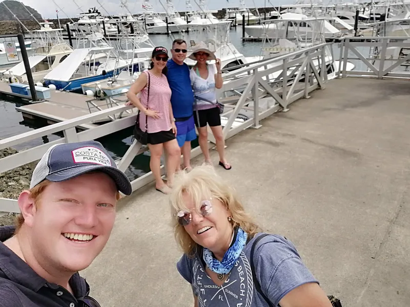 Four people on a marina walkway, moored boats lined up behind them.