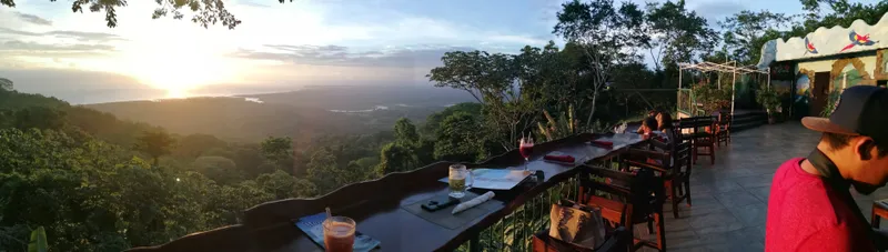 A table set on a railing above the forest, with drinks poured and the sun low.