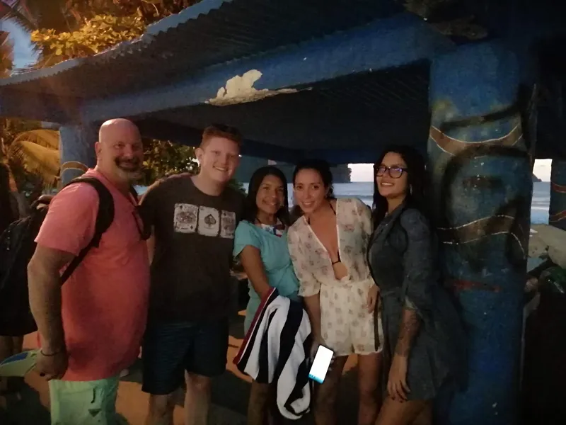 Five people stand together under a roof in low light, posing for the photo.
