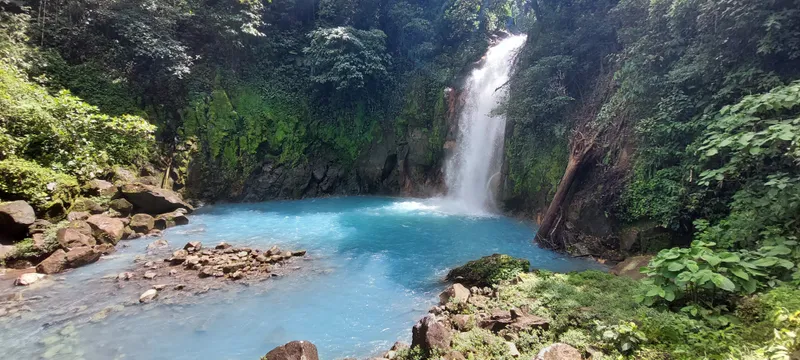 A waterfall drops between mossy rock walls into a pool of turquoise water.